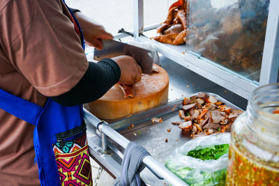 Delicious stewed ear pork at the street food. motion blurred hand of seller chops the pork on board.