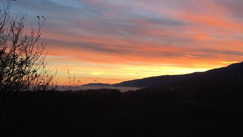 Silhouette landscape against dramatic sky during sunset