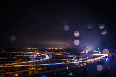 Light trails on highway in city against sky at dusk