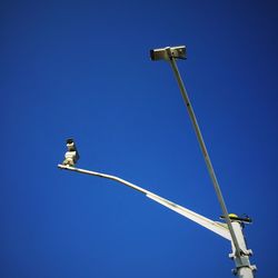 Low angle view of security cameras against clear blue sky