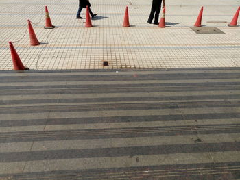 Low section of people on footpath by traffic cones
