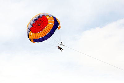 Low angle view of person paragliding against sky