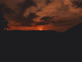 Silhouette landscape against dramatic sky during sunset