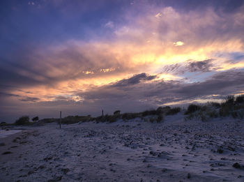 Scenic view of snow covered land against sky during sunset