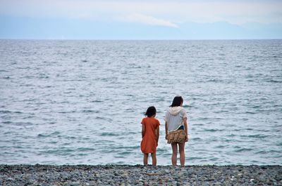 Sisters standing at beach against sky