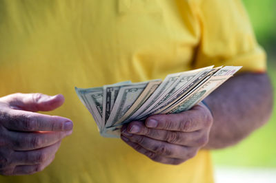 Midsection of man holding paper currency