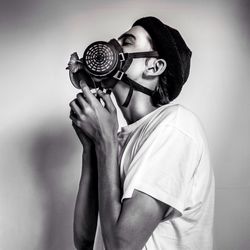 Young man wearing gas mask against wall