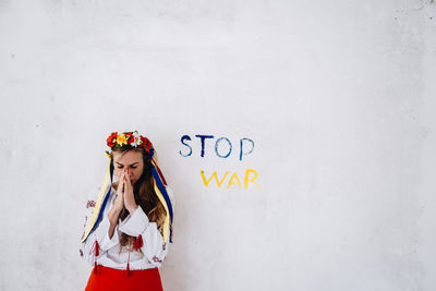 Portrait of young woman standing against wall