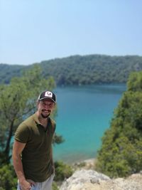 Portrait of smiling man standing on mountain against sea and sky