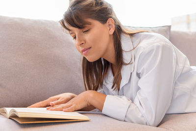 Young woman using mobile phone while lying on bed at home