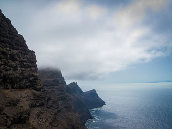 Rock formations by sea against sky