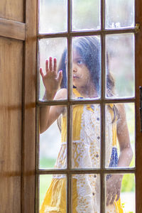 Girl looking through glass window