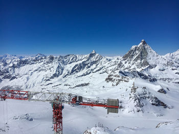 Construction crane on top of klein matterhorn with matterhorn  in the background against blue sky