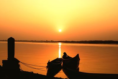 Silhouette boat in sea against orange sky