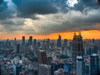 Cityscape against cloudy sky during sunset