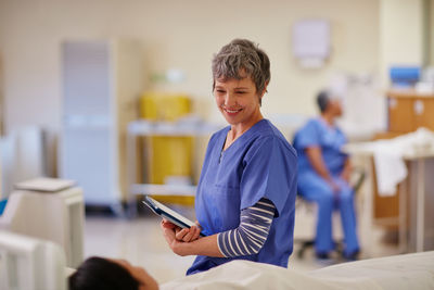 Happy nurse talking to patient in hospital