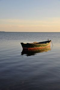 Boat in sea against sky during sunset