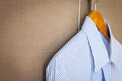 Close-up of shirt hanging on coathanger by window