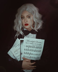 Portrait of woman holding book against black background