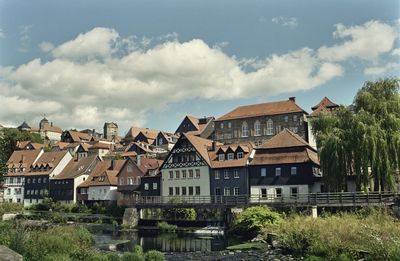 Houses by river and buildings against sky