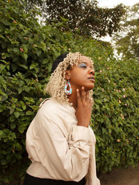 Portrait of young woman standing against plants