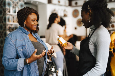 Female coworkers discussing on beauty product in hair salon