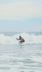 Mid adult man surfing on sea against sky