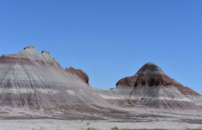 Erosion of sandstone rock layers visible in layers of color in a large mound.