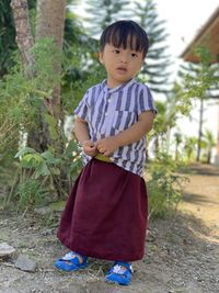 Portrait of boy standing against plants