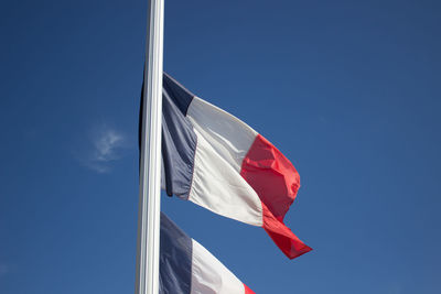 Low angle view of flag against clear blue sky