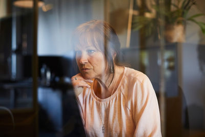 Mature businesswoman using computer seen through glass in office