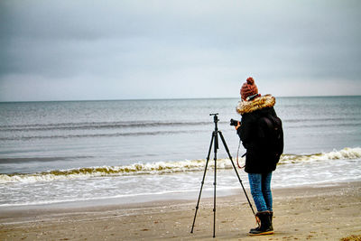 Full length of woman photographing sea against sky