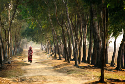 Rear view of woman walking in forest