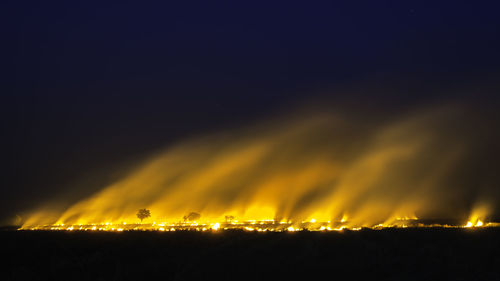 Panoramic view of illuminated lights against sky at night