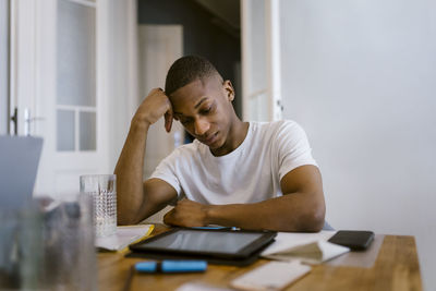 Tired young man leaning on elbow while studying at home