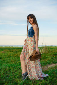 Beautiful young woman in a dress in nature and in a hat