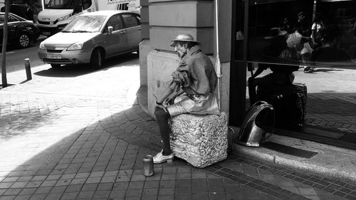 Statue on footpath by street in city