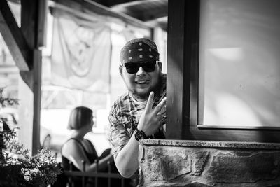 Portrait of young man gesturing peace sign at entrance