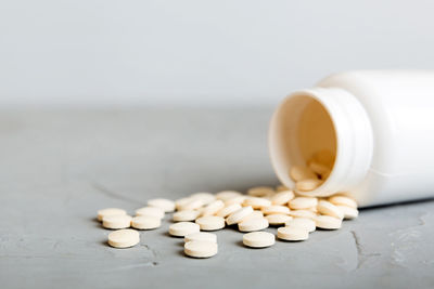 Close-up of pills spilling from bottle on table