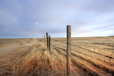 Wooden fence on field against sky