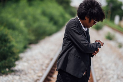 Businessman checking time on railroad track