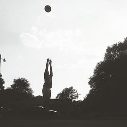 Woman standing by tree against sky