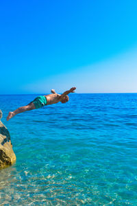 Man diving in sea against clear blue sky