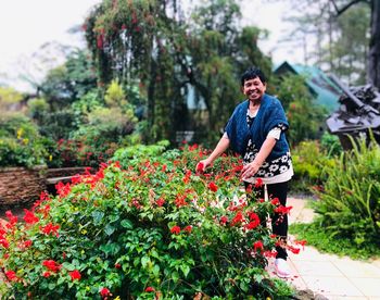 Senior woman standing by flowering plants in garden