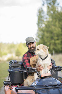 Male farmer with dog driving four-wheeler