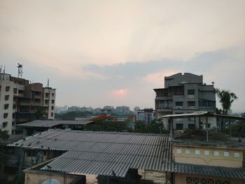 Houses in city against sky during sunset