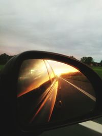 Close-up of side-view mirror against sky