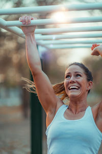 Smiling woman exercising on monkey bars in park