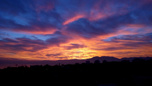 Silhouette landscape against dramatic sky during sunset