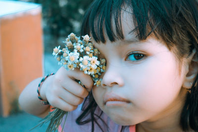 Close-up portrait of girl holding white flower outdoors